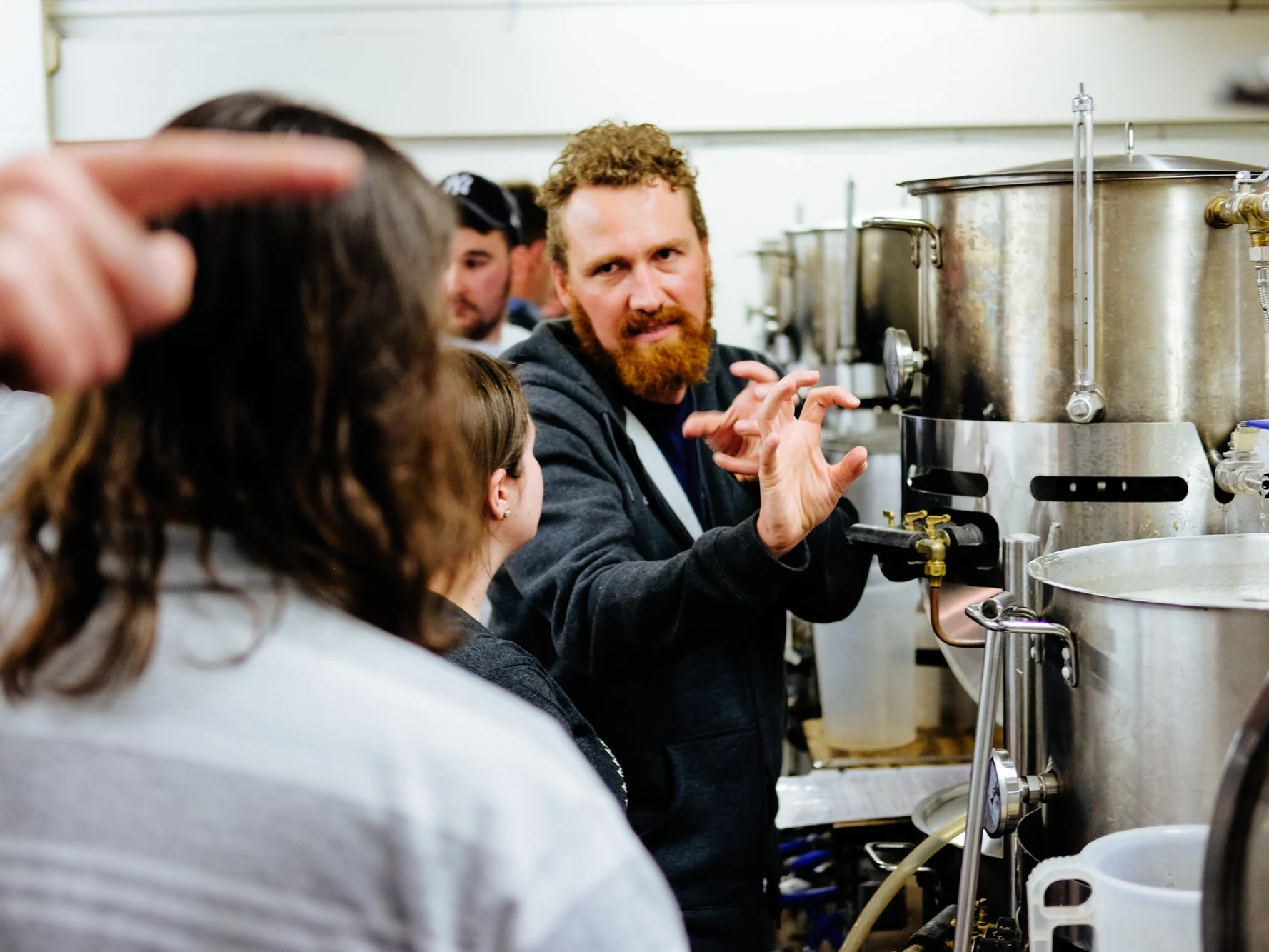 Trent gesturing while explaining the brewing equipment to a group