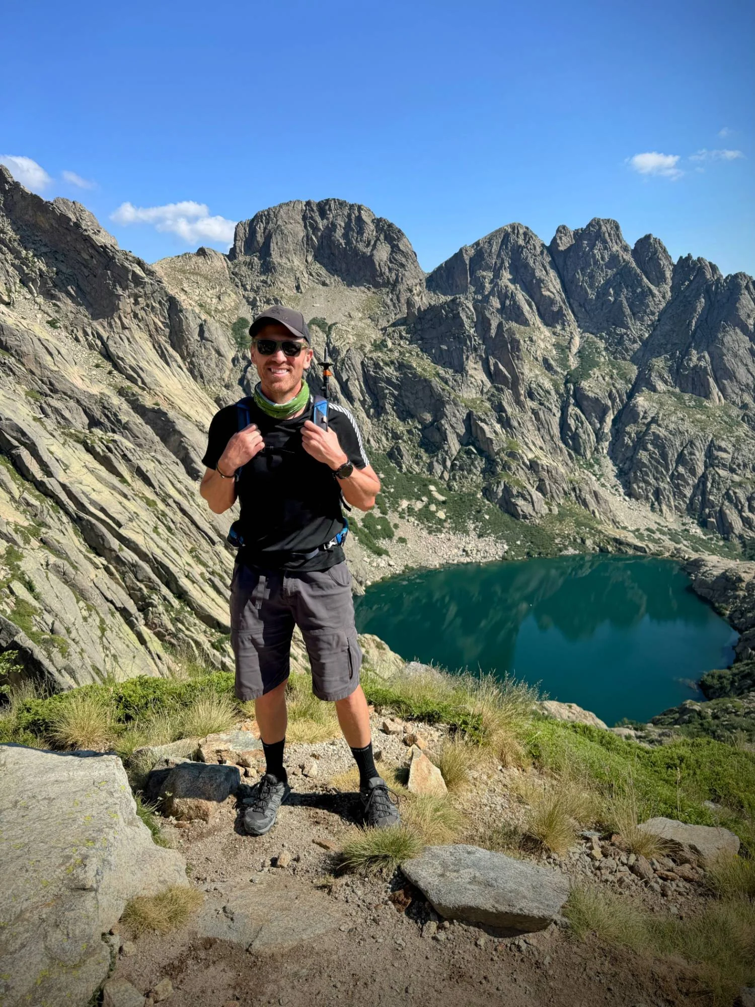 Trent standing on a ridgeline above a turquoise alpine lake in Corsica