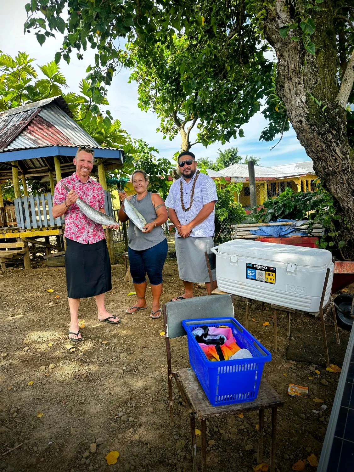 Trent with two locals in Samoa, each holding fish beside a cooler