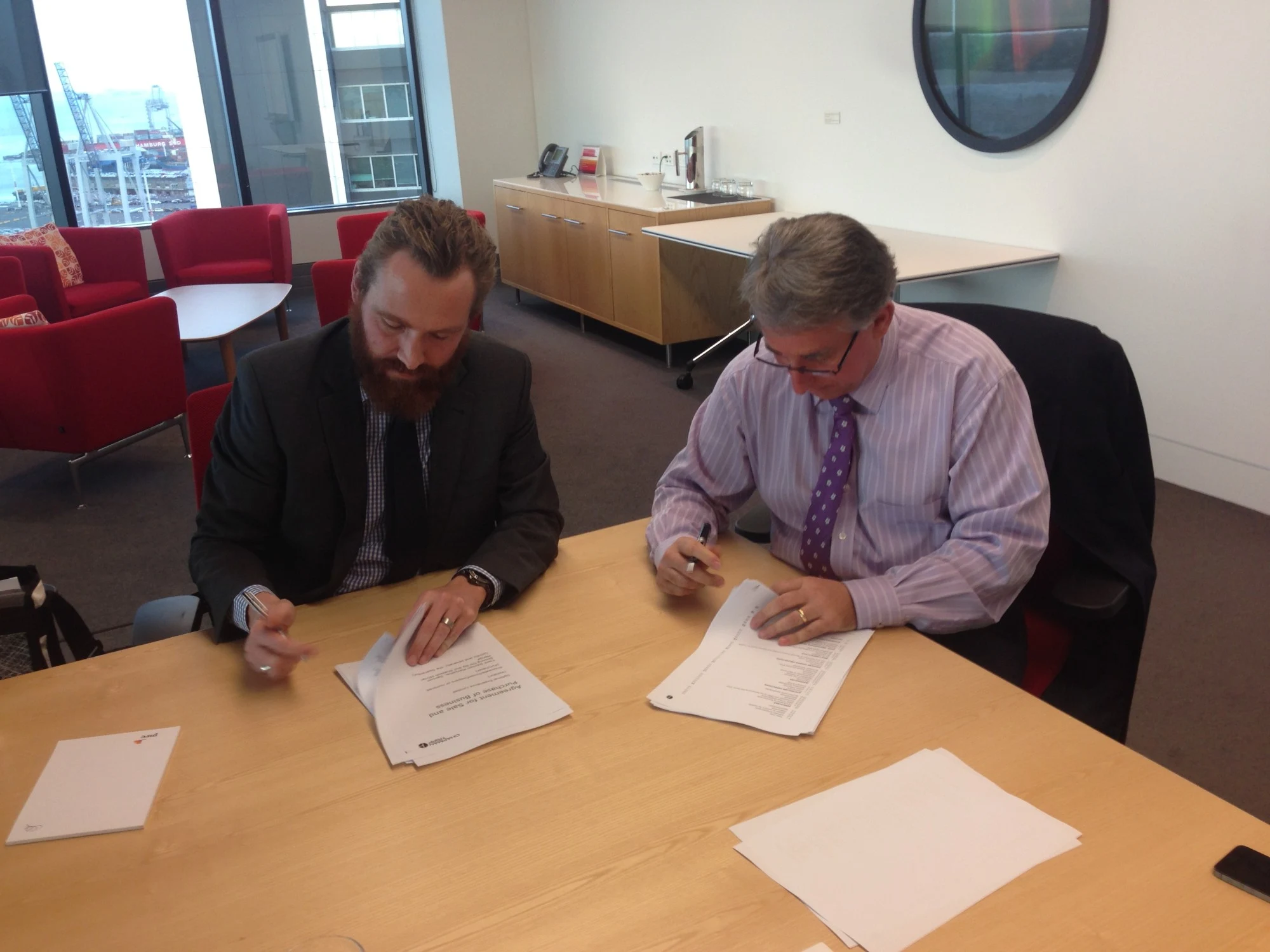 Trent and a PwC representative signing the Agreement for Sale and Purchase of Business