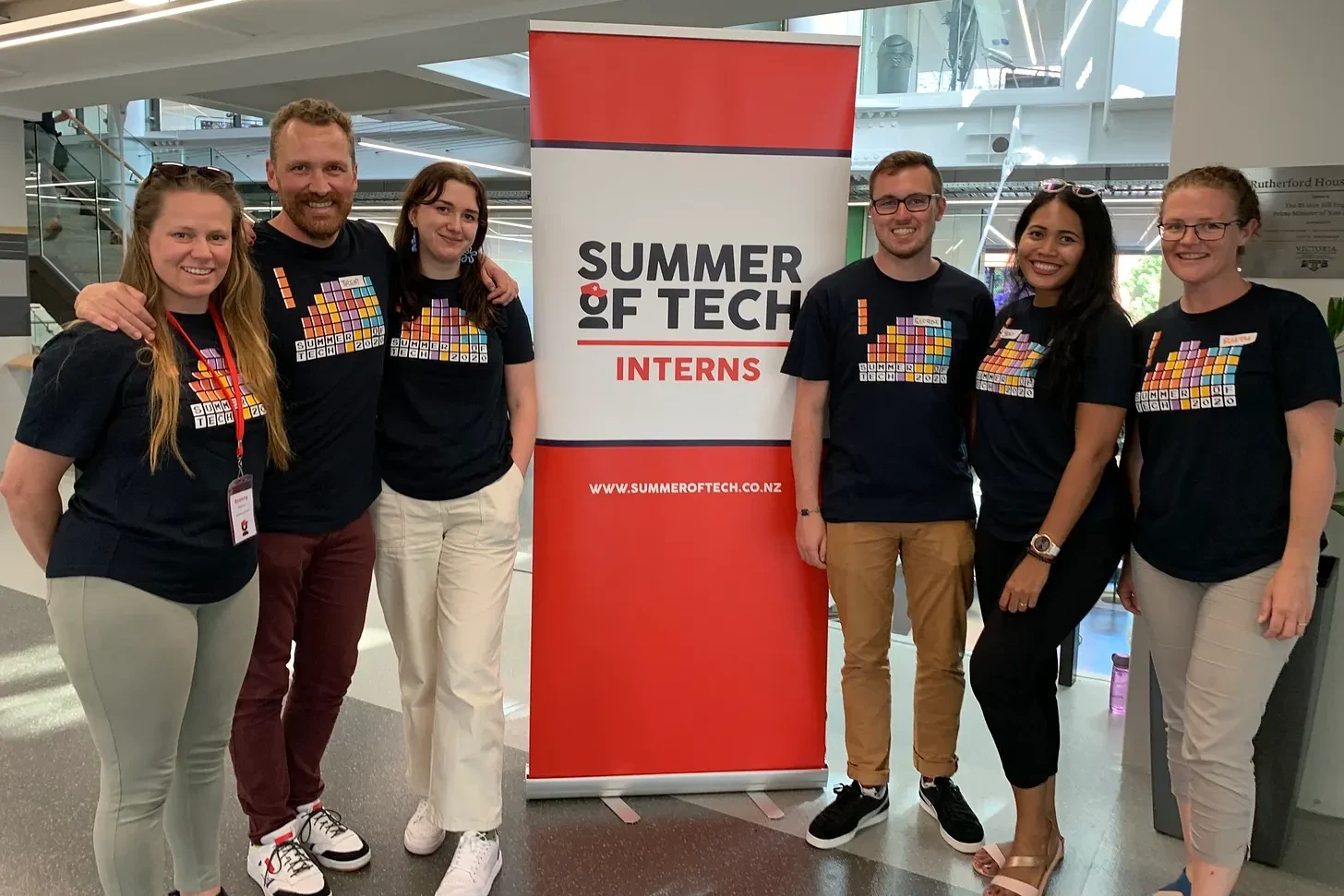 Trent and five Summer of Tech interns posing beside an Interns sign